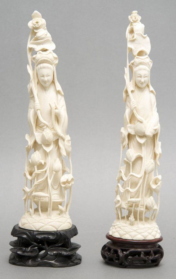 A Group of Two Carved Ivory Figures, Height 12 1/2 inch: A Group of Two Carved Ivory Figures, each of a lady holding a flowering lotus branch, with lotus surrounding the figure upon a wave form base, raised further on a carved wood base. Height 12 1/2 inche