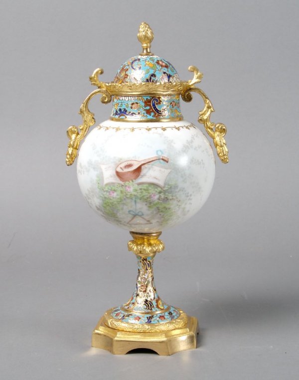 A Continental Porcelain Gilt-Metal and Champleve M: A Continental Porcelain Gilt-Metal and Champleve Mounted Urn and Cover, the spherical body decorated with a putti and a musical trophy, signed E. Dason. Height 10 1/4 inches.