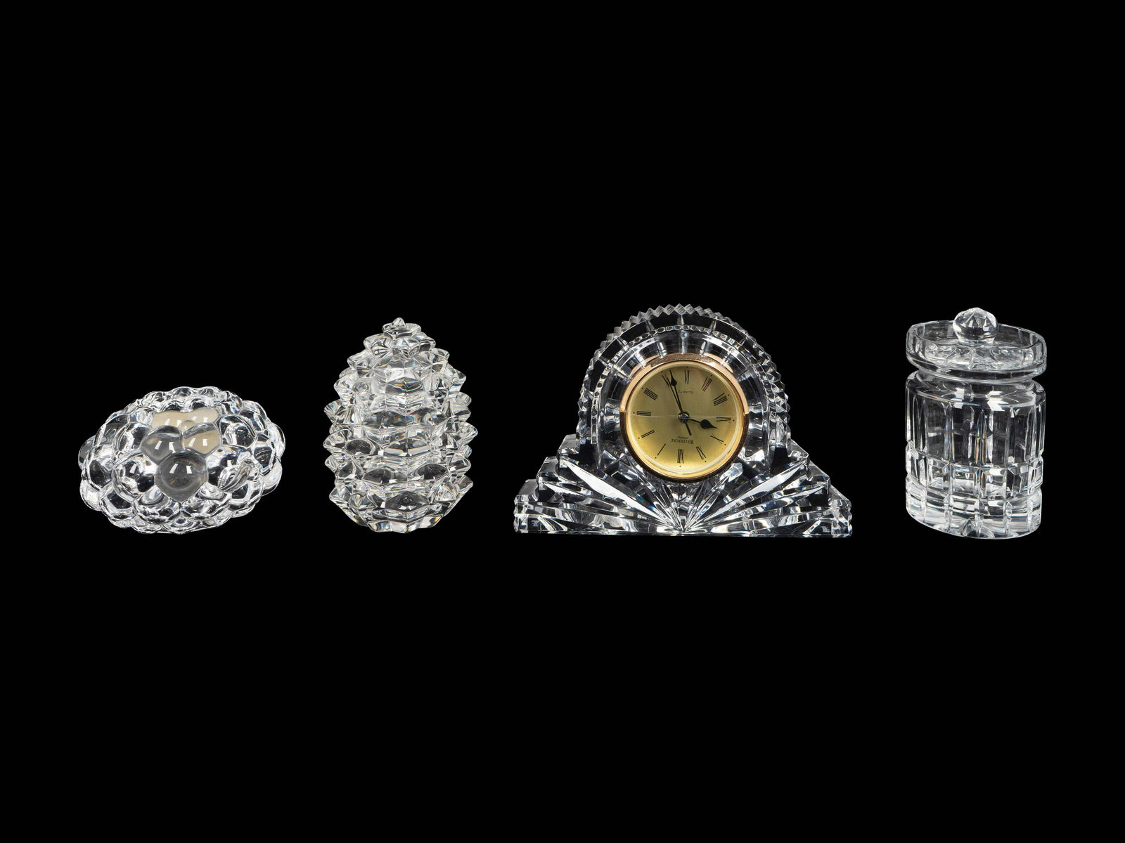 Four Cut Glass Table Articles Height of clock, 4 3/4: Four Cut Glass Table Articles 20TH/21ST CENTURY comprising a Waterford desk clock, a Tiffany Pinecone lidded jar, an Orrefors Raspberry votive and an unsigned lidded jar. Height of clock, 4 3/4 inches