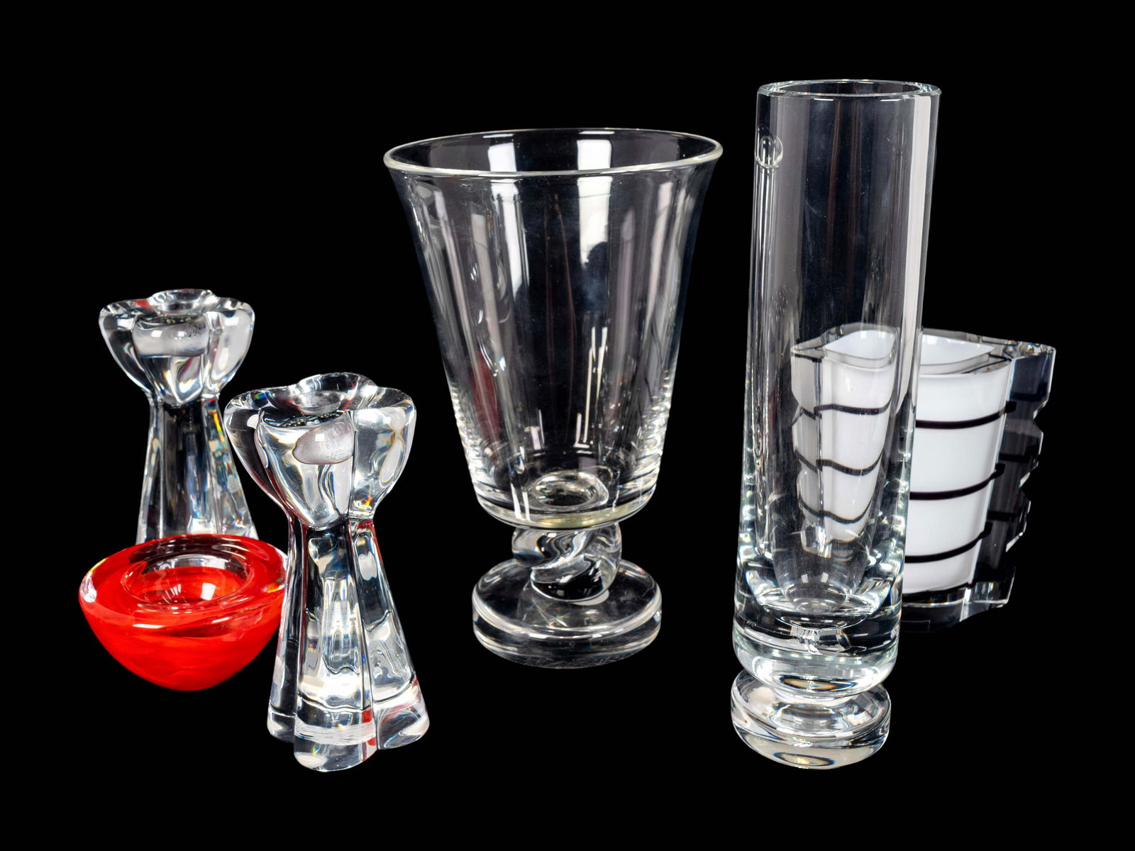 Six Contemporary Glass Table Articles Heights 2 3/8 to: Six Contemporary Glass Table Articles Comprising a Baccarat cylindrical vase, a pair of Baccarat candlesticks, a Steuben vase, a Kosta Boda votive holder and a Kosta Boda cased glass vase. Heights 2 3