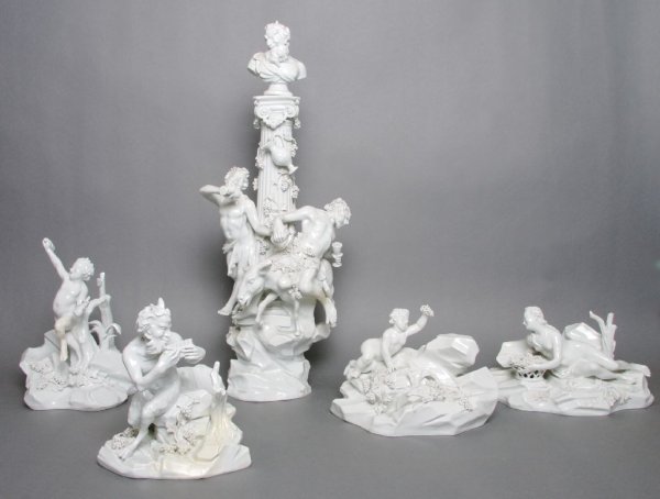 A Capodimonte Blanc de Chine Porcelain Figural Centerpi: A Capodimonte Blanc de Chine Porcelain Figural Centerpiece, after the Meissen model by Johann Joachim Kaendler, comprising a central columnar form surmounted with a satyr's bust, surrounded with vario