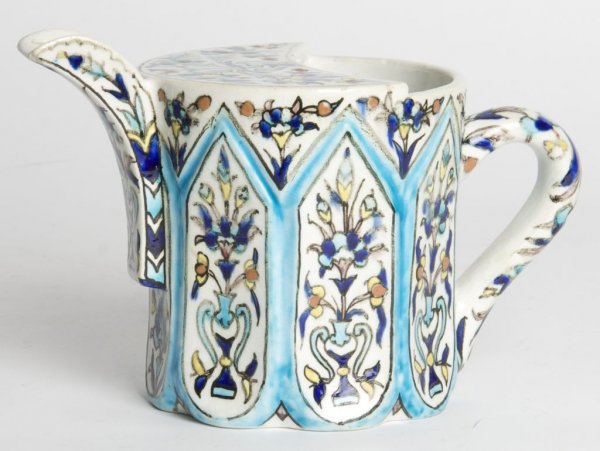 A Middle Eastern Pottery Ewer, Height 4 3/4 inches: A Middle Eastern Pottery Ewer, of faceted cylindrical form, decorated with repeating stylized vases issuing flowers, base marked with Islamic script. Height 4 3/4 inches.