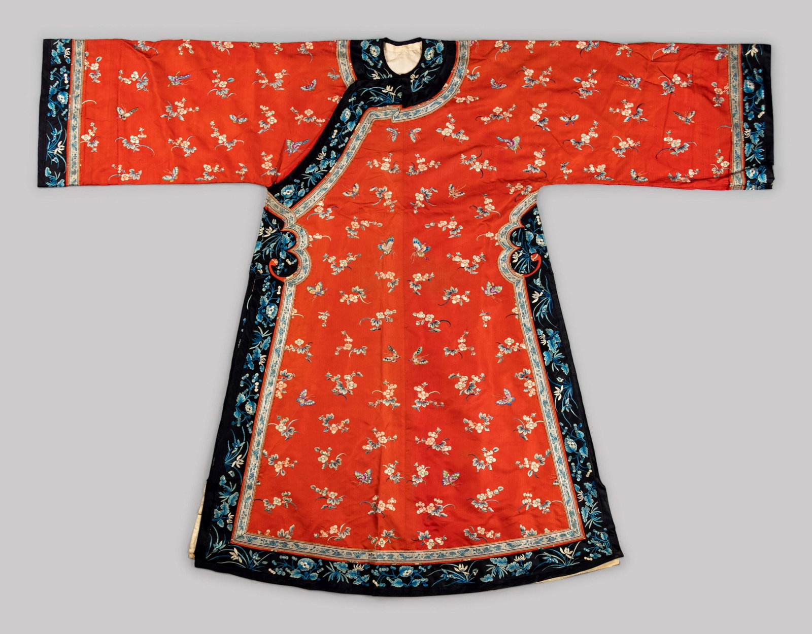 An Apricot Ground Embroidered Silk Ladies' Informal: An Apricot Ground Embroidered Silk Ladies' Informal Robe LATE 19TH-EARLY 20TH CENTURY the body and sleeves evenly embroidered with butterflies and prunus, opening to a flat bordered fret at the side c