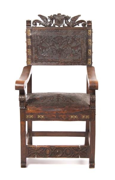 A Renaissance Revival Oak Chair, Height 47 x width: A Renaissance Revival Oak Chair, having a carved top rail depicting two winged dragons flanking an armorial crest over an embossed back and seat having stylized brass upholstery tacks, the whole raise