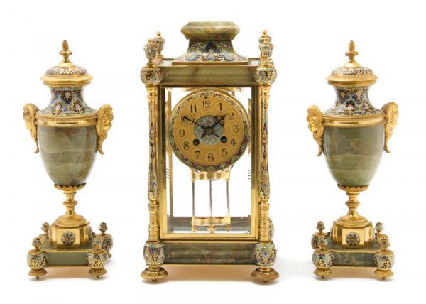 An Onyx and Champleve Clock Garniture Set, Height: An Onyx and Champleve Clock Garniture Set, comprised of a clock and two urns, the clock having a 4-inch gilt dial with Arabic numerals and the urns having acorn form finials and mask form handles. Hei