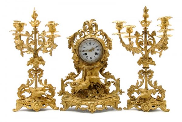A French Gilt Metal Three-Piece Clock Garniture, H: A French Gilt Metal Three-Piece Clock Garniture, the enameled circular dial with Roman hours and Arabic minutes signed Hodel, Strasbourg, set in a scrolling Rococo case decorated with birds, flowers a