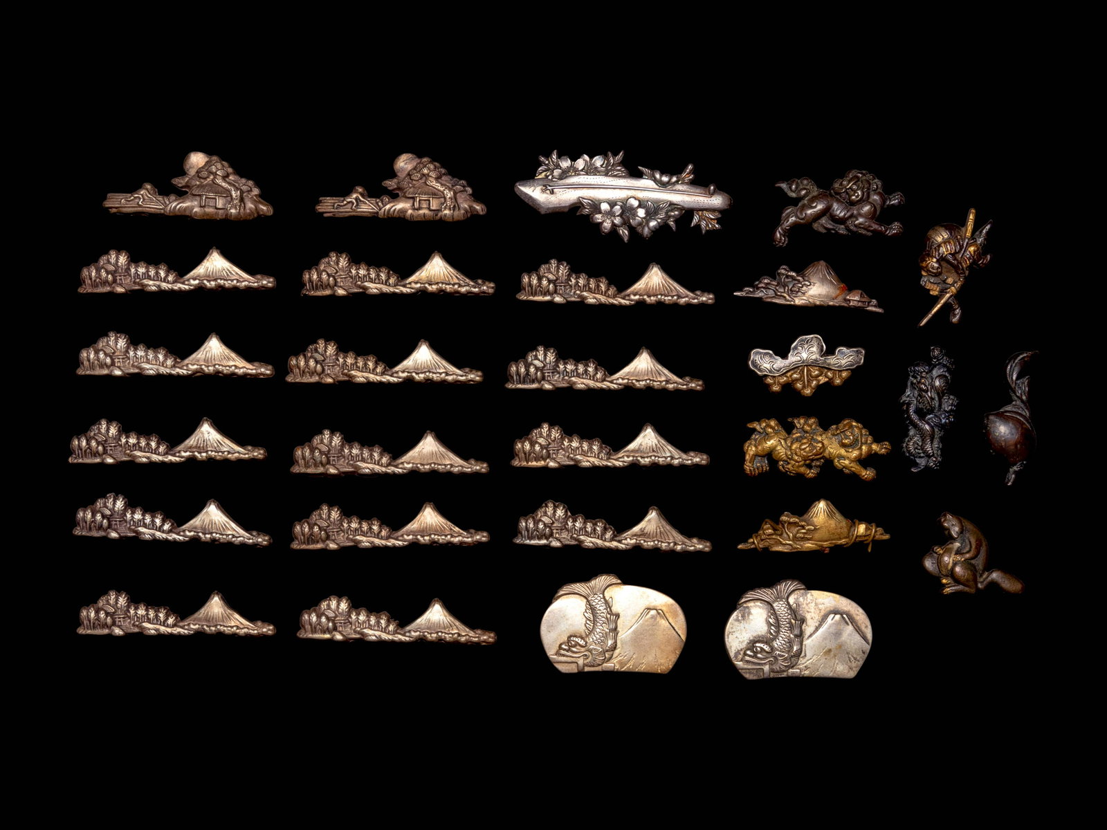 28 Mixed Metal Menuki: 28 Mixed Metal Menuki LATE 18TH/19TH CENTURY comprising 19 examples depicting landscapes, two showing shishi lions, one with relief inlay showing a samurai, one depicting a seated squirrel, one dragon