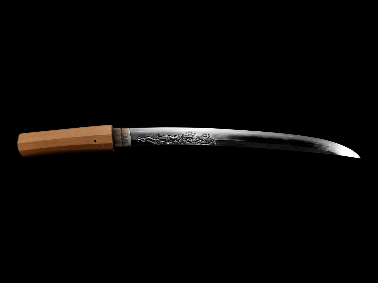 A Wakazashi: A Wakazashi in shirasaya, signed Minamoto Toshimasa Saku Kore, made in the fall of 1867, in Shobuzukuri style, bearing a carving of a dragon on one side. Length of blade 16 in., 40.64 cm. Property fro