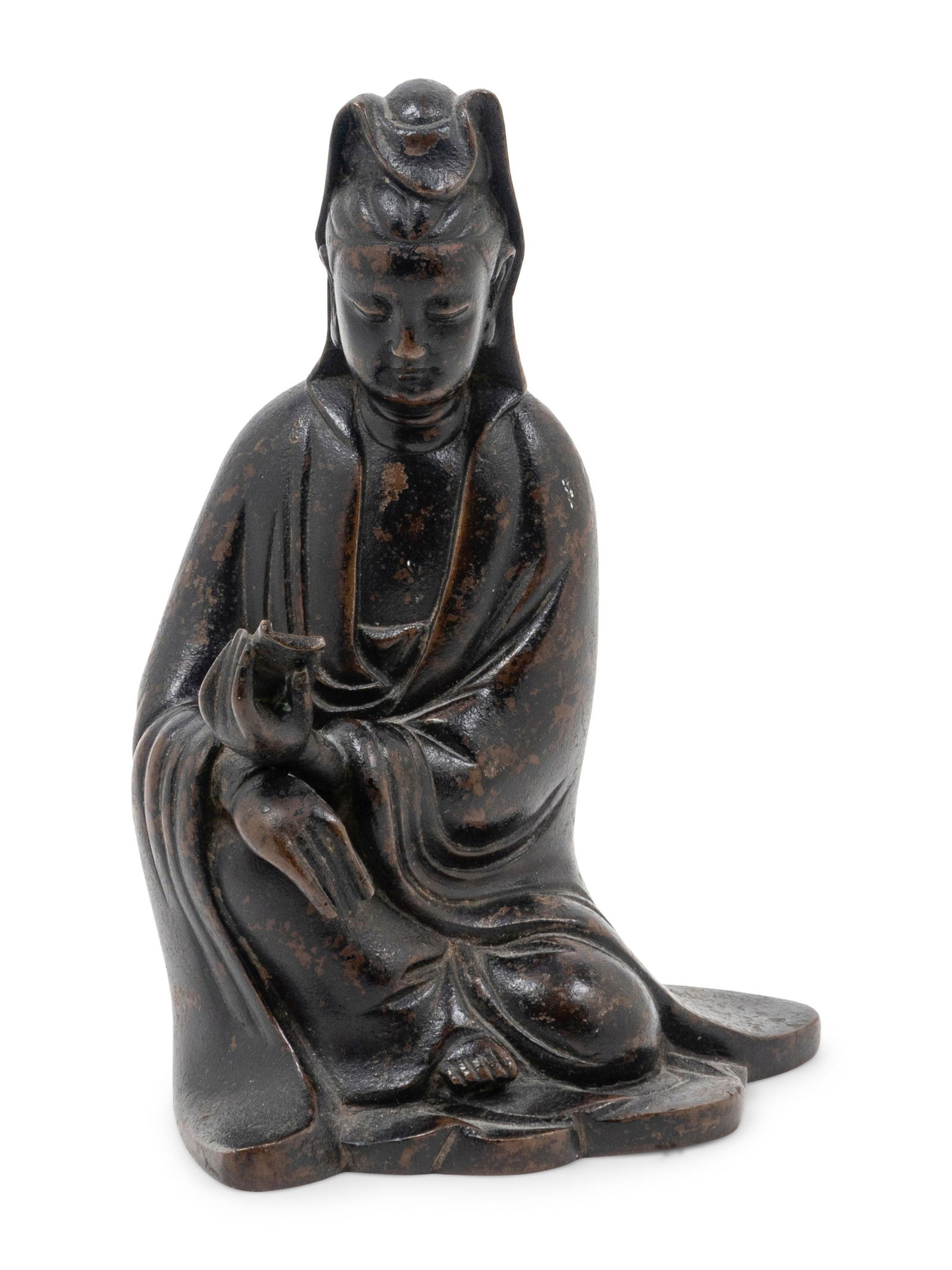 A Chinese Bronze Figure of Guanyin: A Chinese Bronze Figure of Guanyin the figure cast seated with the left leg tucked underneath, clad in draping robes cascading into folds at the waist and pooling at the feet, eyes downcast with a ben