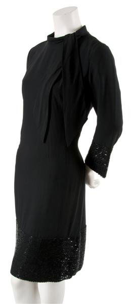 A Galanos Black and Beaded Cocktail Dress,: A Galanos Black and Beaded Cocktail Dress, 1960s, with bugle beading across hemline and cuffs, sash tie at collar. Labeled: Galanos.