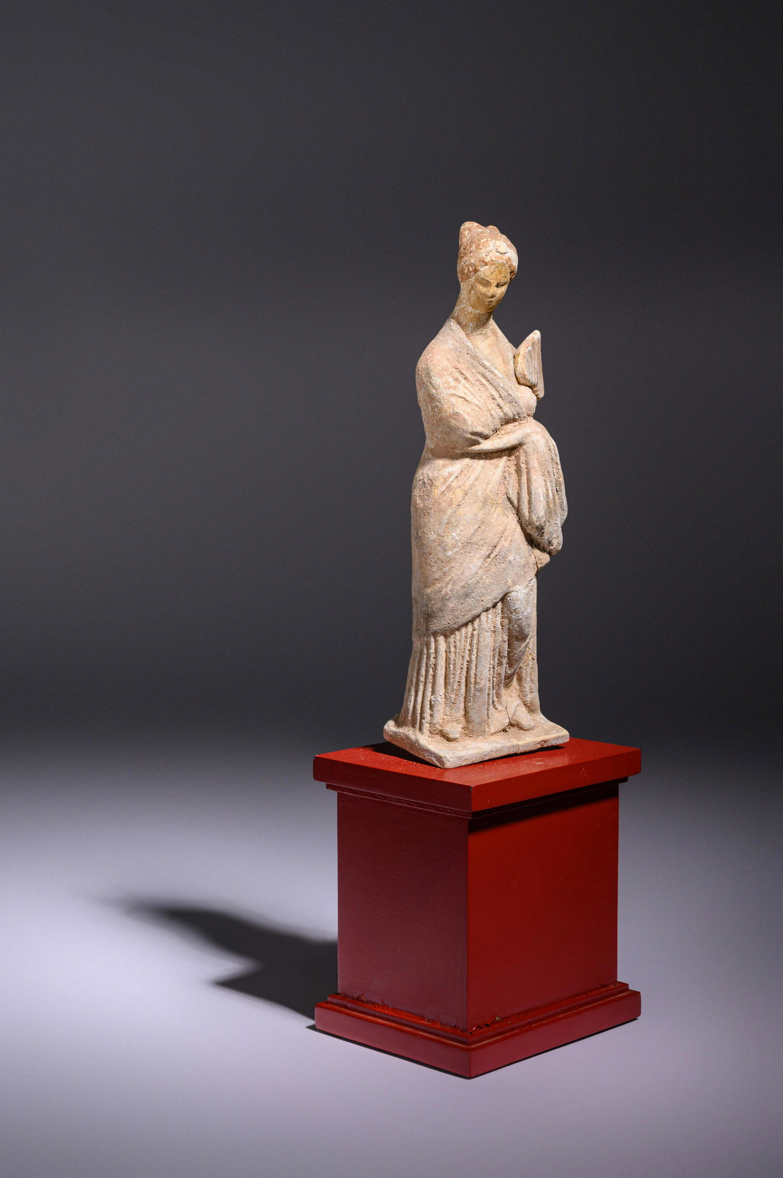 A Greek Terracotta Female with a Fan Height 8 inches.: A Greek Terracotta Female with a Fan Circa 4th-3rd Century B.C. Height 8 inches. Property from the Collection of Georgette D'Angelo, Glencoe, Illinois Provenance: Fortuna Fine Arts, New York, 1989. (w