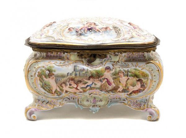 A Capodimonte Porcelain Table Casket, Length 12 1/: A Capodimonte Porcelain Table Casket, of oval form, the whole decorated with cherubs raised on scrolling feet. Length 12 1/4 inches.