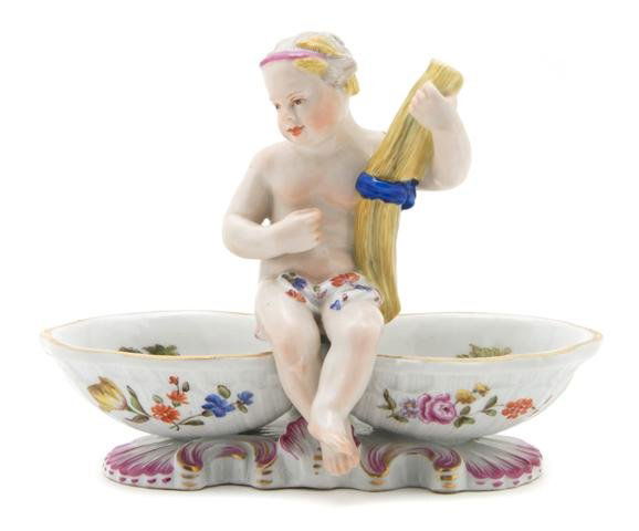 A Meissen Porcelain Double Salt, Length 6 1/2 inch: A Meissen Porcelain Double Salt, depicting a young girl with wheat atop the shaped salts, decorated with courting couples, having crossed swords in underglaze blue, bearing further marks to base. Leng
