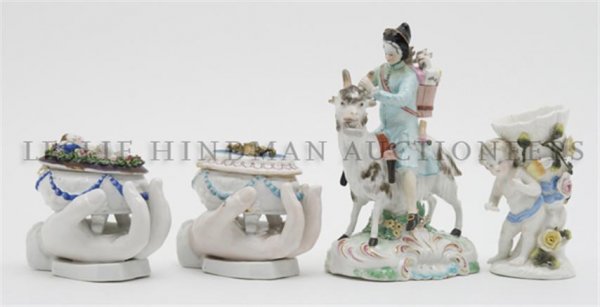 A Collection of Four Continental Porcelain Articles, He: A Collection of Four Continental Porcelain Articles, comprising a man on a goat, a putti with a vase and two table caskets mounted on hand form bases. Height of first 7 1/4 inches.