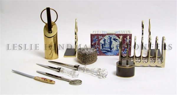 A Collection of Desk Articles, Height of first 7 1/2 in: A Collection of Desk Articles, comprising a brass letter opener and scissors rack, a pair of brass bookends, a Delft flower frog, four letter openers, a silverplate heart shaped box, a silverplate let