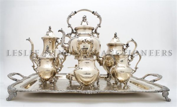 An English Silverplate Tea Service, Width of tray over : An English Silverplate Tea Service, comprising a teapot, coffee pot, kettle on stand, waste pot, creamer and sugar, the lids having a floriform finial, together with a double handled tray with gadroon