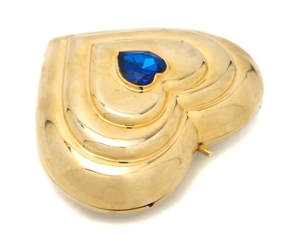 An Yves Saint Laurent Heart Shaped Evening Bag, 7 x 5 i: An Yves Saint Laurent Heart Shaped Evening Bag, goldtone with a blue crystal at center, hidden long cord shoulder strap. Stamped: Yves Saint Laurent. 7 x 5 inches.