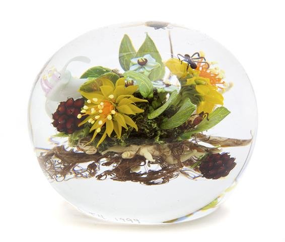 A Paul Stankard Glass Paperweight, Diameter 3 1/4 inche: A Paul Stankard Glass Paperweight, the clear glass of round form, enclosing a hovering bee over a botanical arrangement comprising white flowers, yellow flowers and berries interspersed with leaves, a