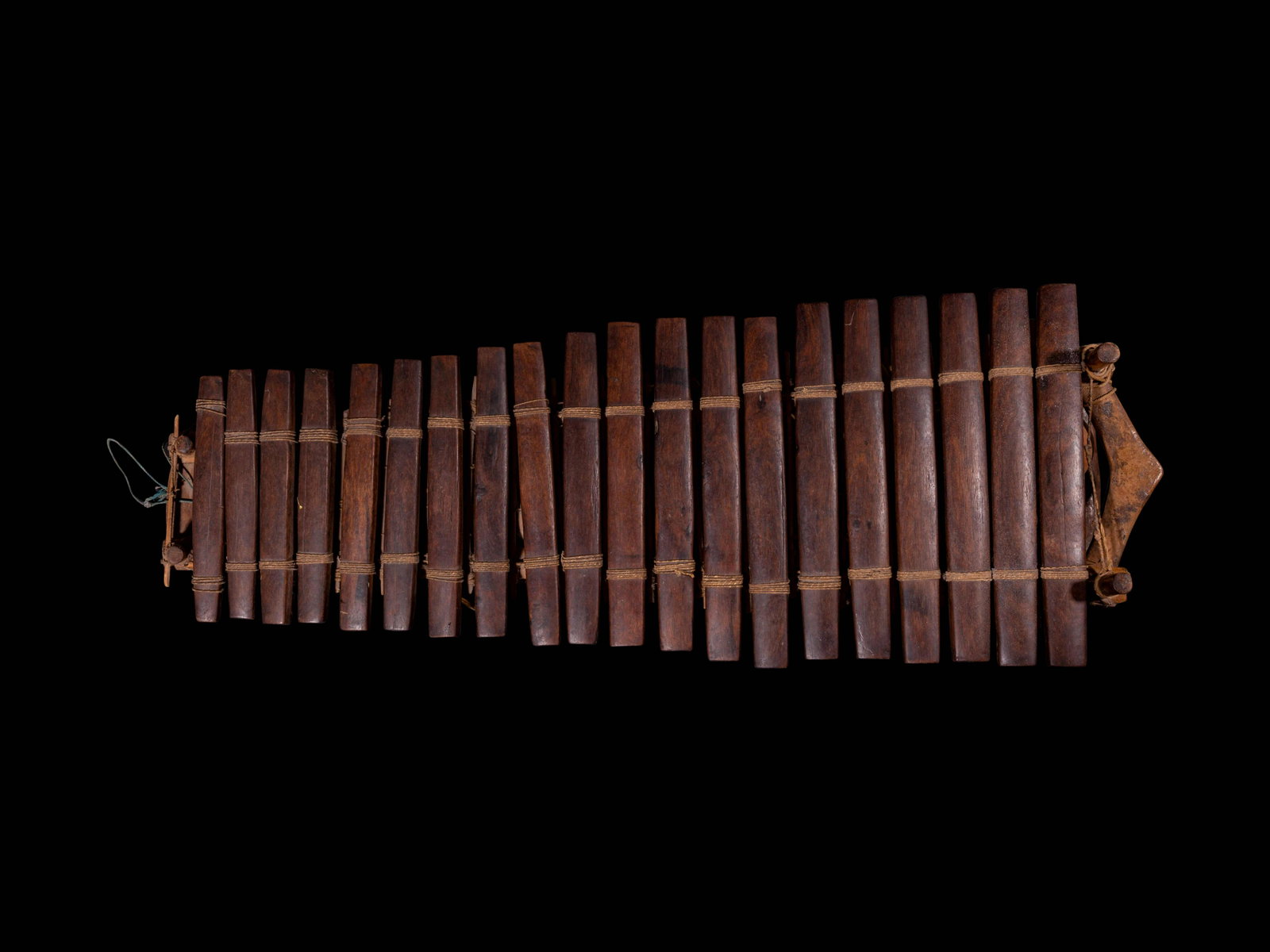 A ChineseHuanghualiMusical Instrument: A Chinese Huanghuali Musical Instrument the percussive instrument comprised of various smooth panels bound in descending size above a arrow-form frame. Length 46 in., 117 cm.