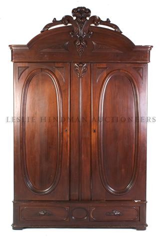 A Victorian Armoire, Height 114 1/2 x width 73 3/4 x de: A Victorian Armoire, the domed cornice with fruit and leaf crest over the two paneled doors above two drawers. Height 114 1/2 x width 73 3/4 x depth 23 1/4 inches.