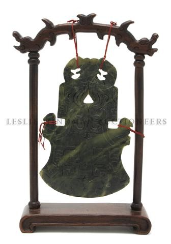 A Spinach Green Hardstone Blade, Height of blade 7: A Spinach Green Hardstone Blade, having archaistic carved decoration, suspended from a hardwood stand. Height of blade 7 3/8 inches. Property from the Collection of Greg Peterson, Kettering, Ohio