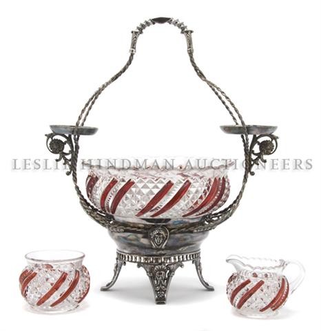 A Silverplate and Pressed Glass Epergne, Height 15: A Silverplate and Pressed Glass Epergne, having a central basket and a creamer and sugar each with ruby staining raised on foliate and mask feet. Height 15 inches. Property from the Collection of Greg