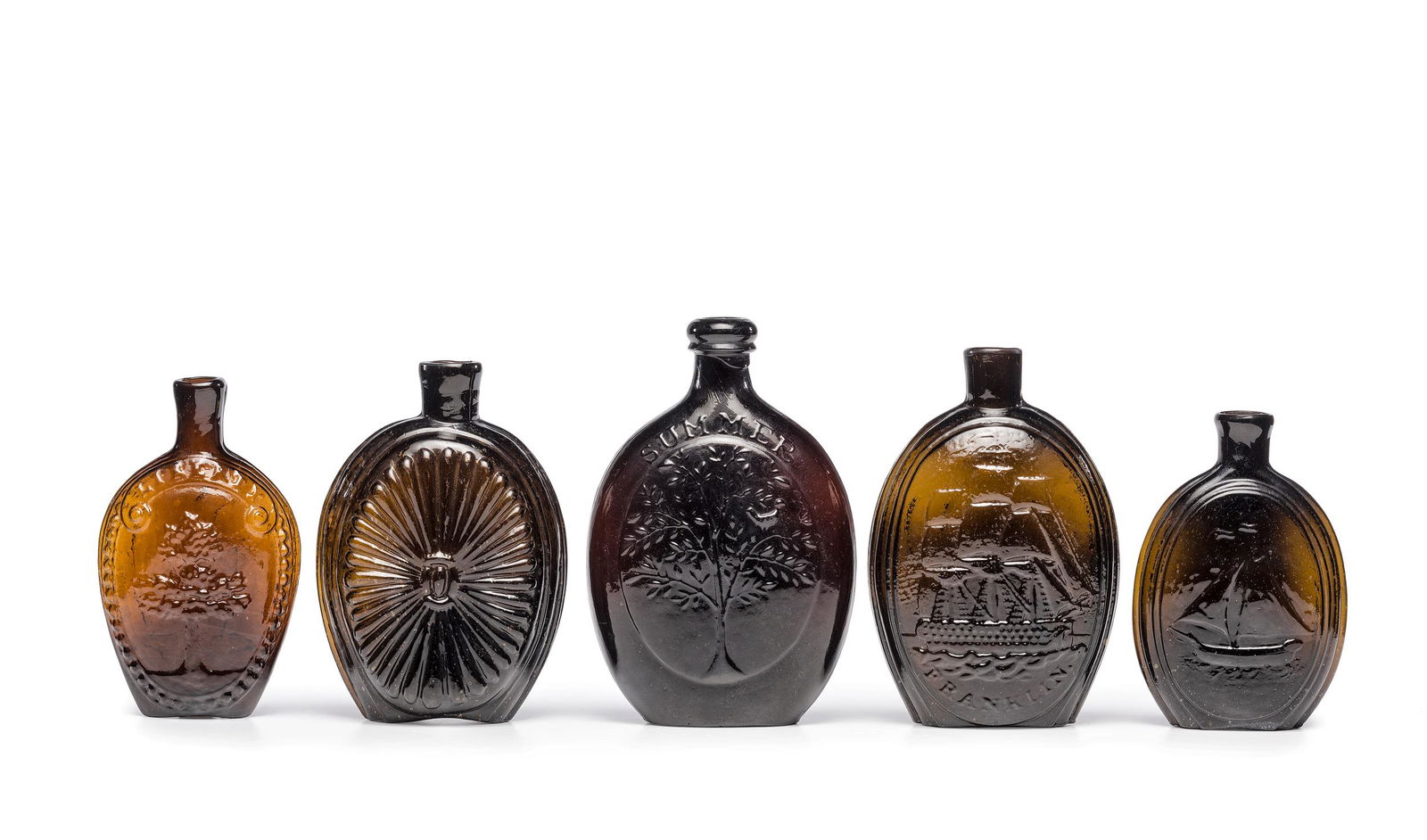 Five Molded Glass Amber Flasks: Five Molded Glass Amber Flasks American, 19th Century one half-pint circa 1824-1840 having a tree on one side, an eagle on other side, Height 6 inches. one pint circa 1824-1840 likely by Kensington Gl