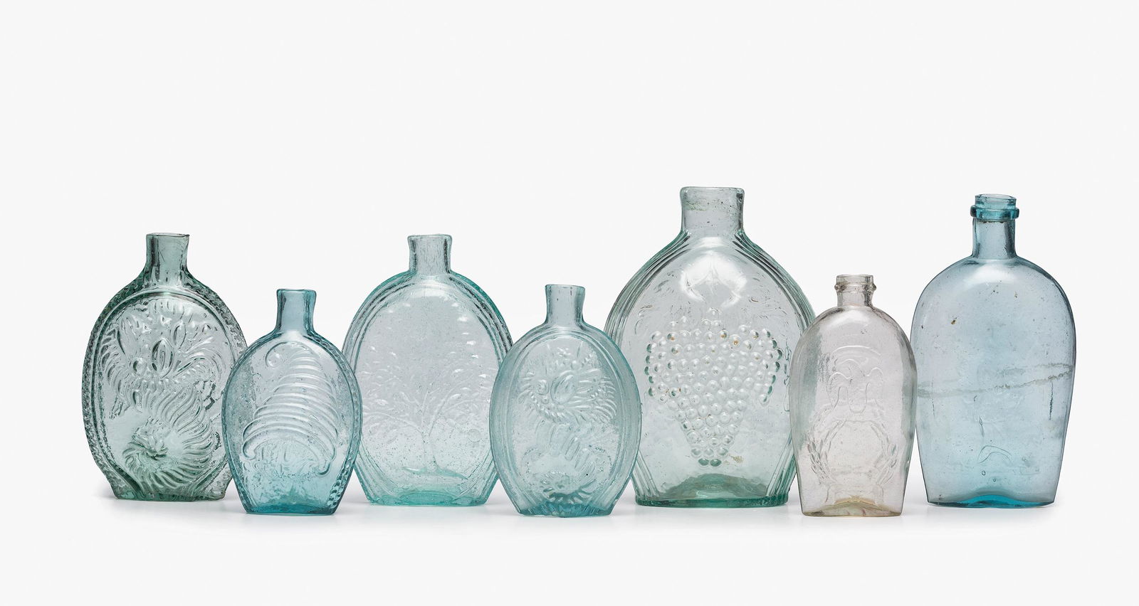 Seven Molded Glass Aqua and Clear Flasks: Seven Molded Glass Aqua and Clear Flasks American, 19th Century one half-pint circa 1824-1840 likely from Pittsburgh having an American eagle on one side, a cornucopia on the other, Height 5 1/2 inche
