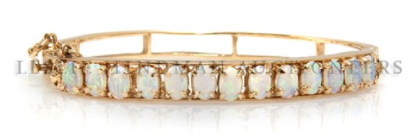 A 14 Karat Yellow Gold and Opal Bangle Bracelet, 11.25 : A 14 Karat Yellow Gold and Opal Bangle Bracelet, containing 13 oval cabochon cut opals weighing approximately 3.90 carats total. Stamp: 14K. 11.25 dwts.