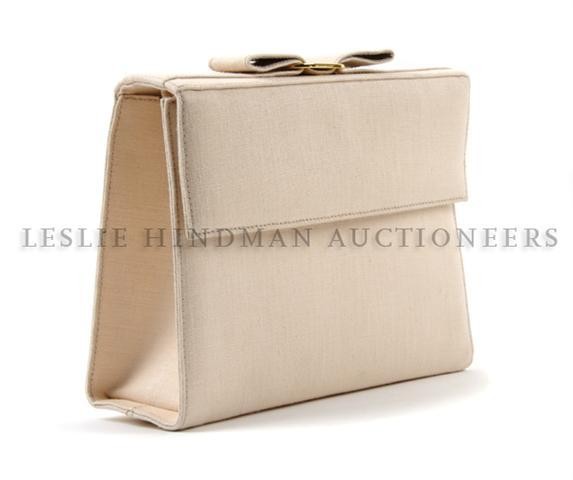 A Ferragamo Pink Linen Clutch, 9 x 6 1/2 inches.: A Ferragamo Pink Linen Clutch, with magnetic flap closure, bow and gold tone buckle, detachable long strap, one interior pocket. Stamped: Salvatore Ferragamo/Made in Italy. 9 x 6 1/2 inches.