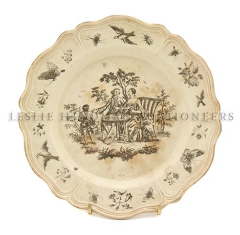 An Early English Creamware Plate, Diameter 7 3/4 i: An Early English Creamware Plate, 18th century, the center having scene of a picnicing couple in period dress with an attendant pouring tea, the border having floral sprays, insects and birds inside o