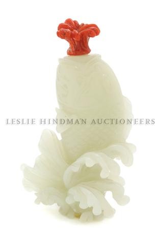 A Jade Fish Form Snuff Bottle, Height overall 3 1/2: A Jade Fish Form Snuff Bottle, the bottle depicting an upward facing fish raised upon a wave like base, the stopper of carved salmon colored coral in the form of a plume of water. Height overall 3 1/2
