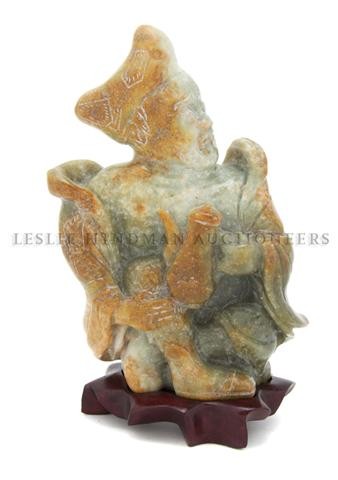 A Carved Jade Figure of a Monk, Height 6 inches.: A Carved Jade Figure of a Monk, depicting the Manchurian monk in flowing robes and hat, carved of celadon colored stone with some areas of russet coloring. Height 6 inches.