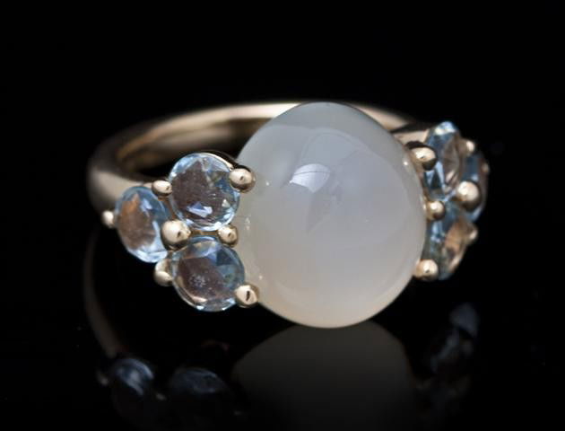 An 18 Karat Yellow Gold, Moonstone and Aquamarine: An 18 Karat Yellow Gold, Moonstone and Aquamarine Ring, Pomellato, containing one oval cabochon cut moonstone measuring approximately 12.80 x 11.30 mm and six round checkerboard top aquamarines weighi