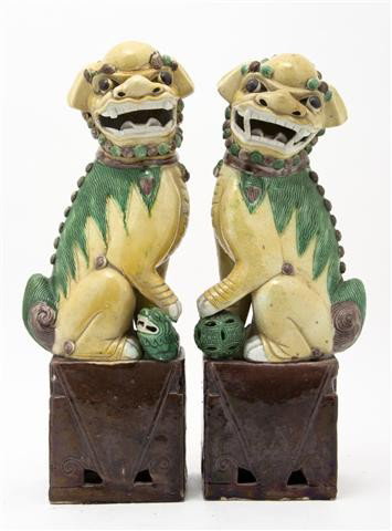A Pair of Chinese Fu Dogs, Height 17 inches.: A Pair of Chinese Fu Dogs, of typical form and pose, with yellow reserve and green mane raised upon a rectangular base. Height 17 inches. Property from the Estate of Norma Stone, Chicago, Illinois