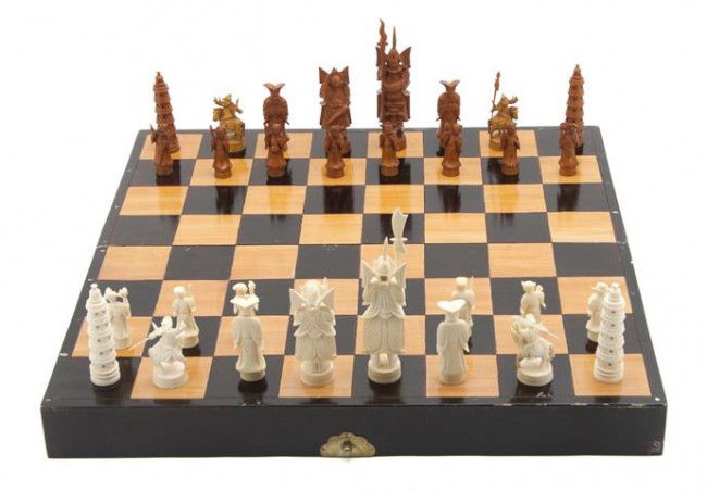 A Carved Ivory and Boxwood Chess Set, Width of boa: A Carved Ivory and Boxwood Chess Set, of typical form, comprising a chessboard and playing pieces. Width of board 17 7/8 x length 18 6/8 inches.
