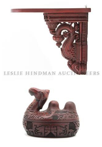 A Balinese Carved Wood Wall Bracket, Height of fir: A Balinese Carved Wood Wall Bracket, of scrolling design with red painted finish throughout, together with a camel form lidded box. Height of first 10 1/4 inches.