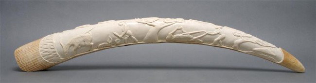 An African Carved Elephant Tusk, Length 36 inches.: An African Carved Elephant Tusk, the ivory tusk carved in relief and depicting a hunting scene. Length 36 inches.