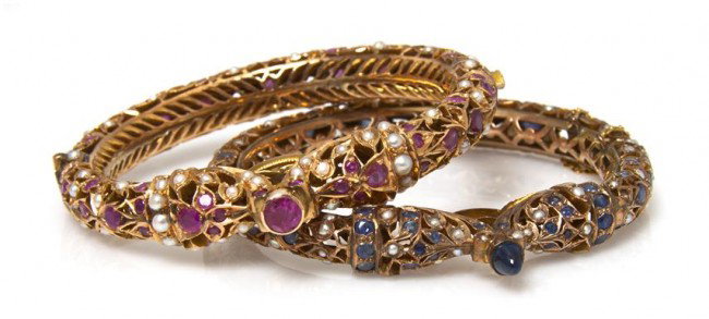 A Pair of Yellow Gold and Multi Gemstone Bangle Br: A Pair of Yellow Gold and Multi Gemstone Bangle Bracelets, in a Mughal style, one bracelet containing numerous round brilliant cut rubies and cultured pearls pearl, the other containing numerous round