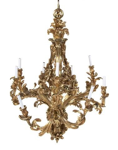 A Louis XV Style Gilt Bronze Chandelier, after the: A Louis XV Style Gilt Bronze Chandelier, after the Model by Jacques Caffieri, the open tripartite standard mounted with six putti musicians and issuing the nine acanthus cast candle arms in clusters o