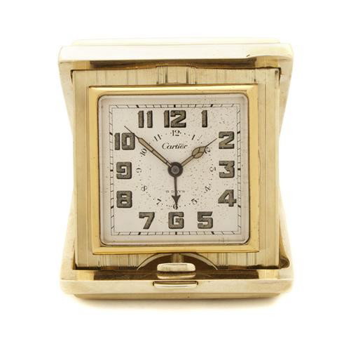 An American 14 Karat Gold Travel Clock, Cartier, W: An American 14 Karat Gold Travel Clock, Cartier, the rectangular case having linear decoration opening to a square dial with Arabic numerals. Width 3 1/2 inches. Property from the William H. Moore Tru