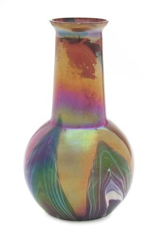 An Austrian Iridescent Glass Vase, in the manner o: An Austrian Iridescent Glass Vase, in the manner of Loetz, of bottle form, with pulled decoration on an iron red ground. Height 7 7/8 inches. Property from the Estate of John Haight, Arlington Heights