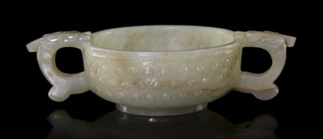 A Chinese Archaistic Style Jade Cup, Width over han: A Chinese Archaistic Style Jade Cup, 19th century, having raised bosses throughout flanked by c-form handles. Width over handles 5 inches. Property from the William H. Moore Trust, Hobe Sound, Florida