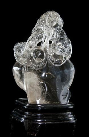 A Carved Quartz Model of a Dragon, Height 6 1/8 inc: A Carved Quartz Model of a Dragon, the beast depicted clutching a sphere above a naturalistic style boulder, having a rutilated area near the base. Height 6 1/8 inches. Property of a Private Collector