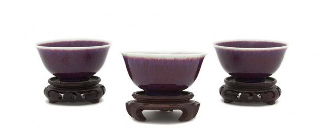 A Group of Three Sang de Boeuf Glazed Bowls, Diame: A Group of Three Sang de Boeuf Glazed Bowls, of flared form with two carved wood stands, unmarked. Diameter 4 1/8 inches. Property from the Estate of Medard C. Lange, Chicago, Illinois