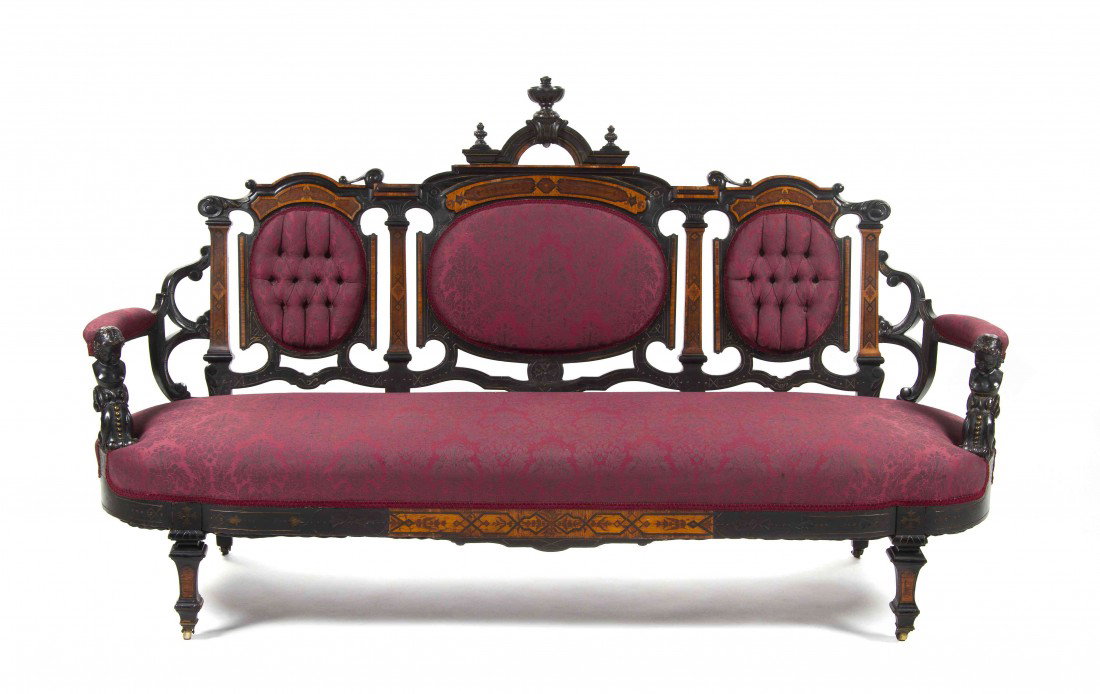 An American Ebonized and Burlwood Triple Back Sett: An American Ebonized and Burlwood Triple Back Settee, second half 19th century, having urn form finials over the upholstered back, arms and seat within a figural and foliate carved frame, raised on sq
