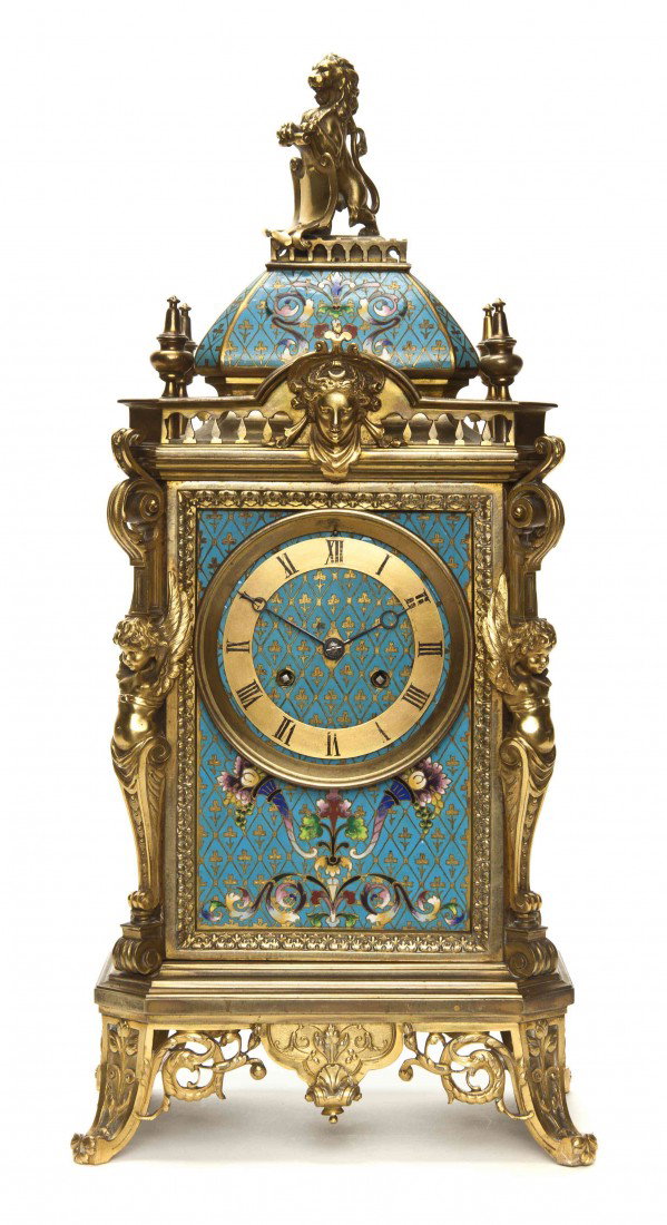 A French Gilt Bronze and Champleve Mantel Clock, H: A French Gilt Bronze and Champleve Mantel Clock, having a lion and shield finial over the rectangular case centered with a circular dial having Roman numerals flanked by winged caryatids, raised on pi