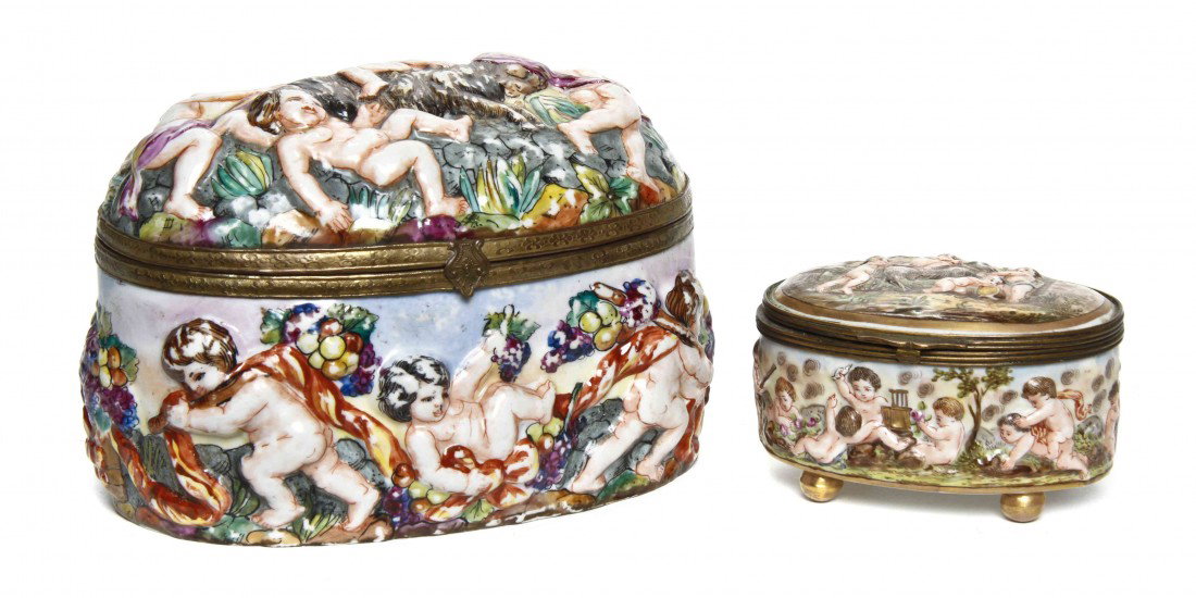 A Capodimonte Porcelain Table Casket, Width of fir: A Capodimonte Porcelain Table Casket, of oval form, decorated with putti in relief throughout, together with a smaller example. Width of first 7 1/4 inches.