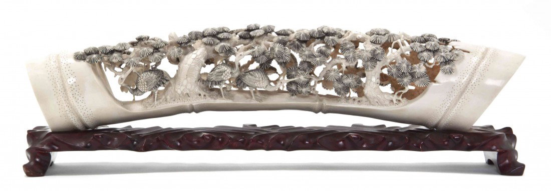 A Chinese Carved Ivory Tusk, Length 20 inches.: A Chinese Carved Ivory Tusk, the section of tusk carved to resemble a segment of bamboo, with pierced carving of cranes below pine trees, raised on fitted wood stand. Length 20 inches.