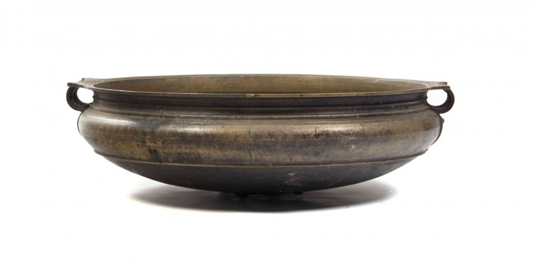 A Southeast Asian Bronze Basin, Diameter 38 inches: A Southeast Asian Bronze Basin, having concentric bands of decoration with scrolled handles over raised ruyi head form decoration. Diameter 38 inches.